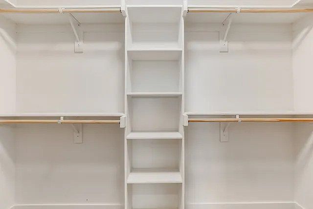 A walk in closet with lots of shelves and hanging racks.