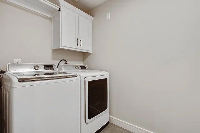 A laundry room with a washer and dryer and white cabinets.
