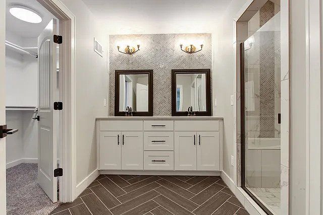 A bathroom with two sinks and a walk in shower.