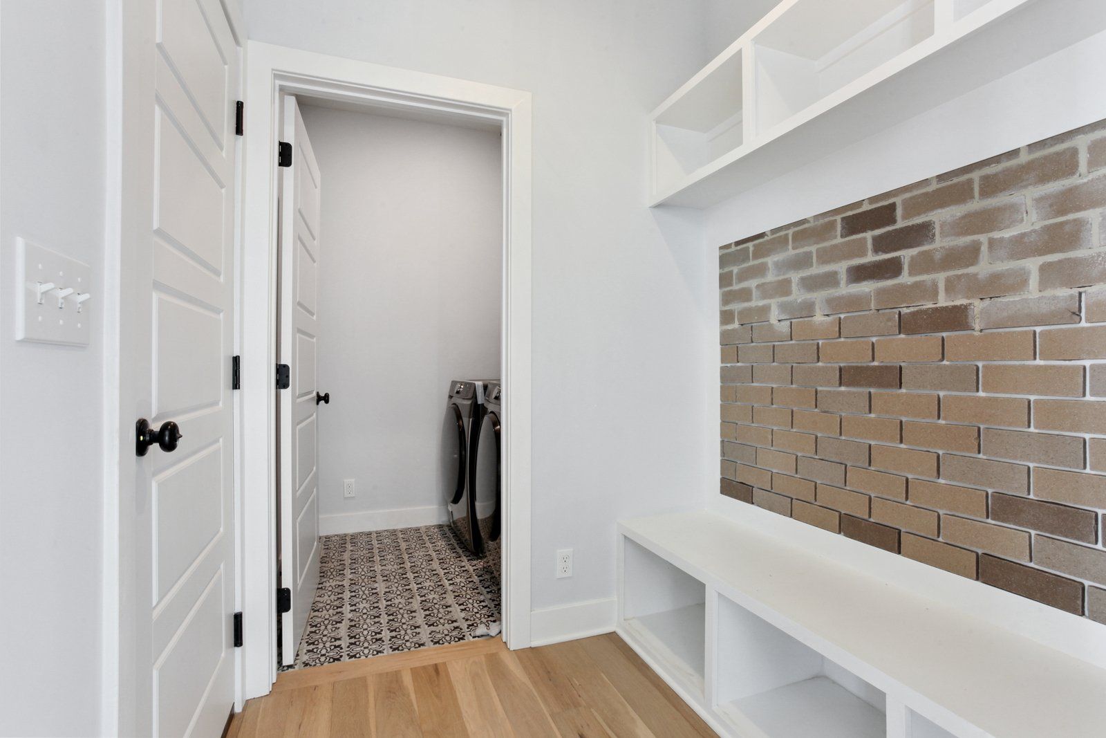 A laundry room with a brick wall and a washer and dryer.