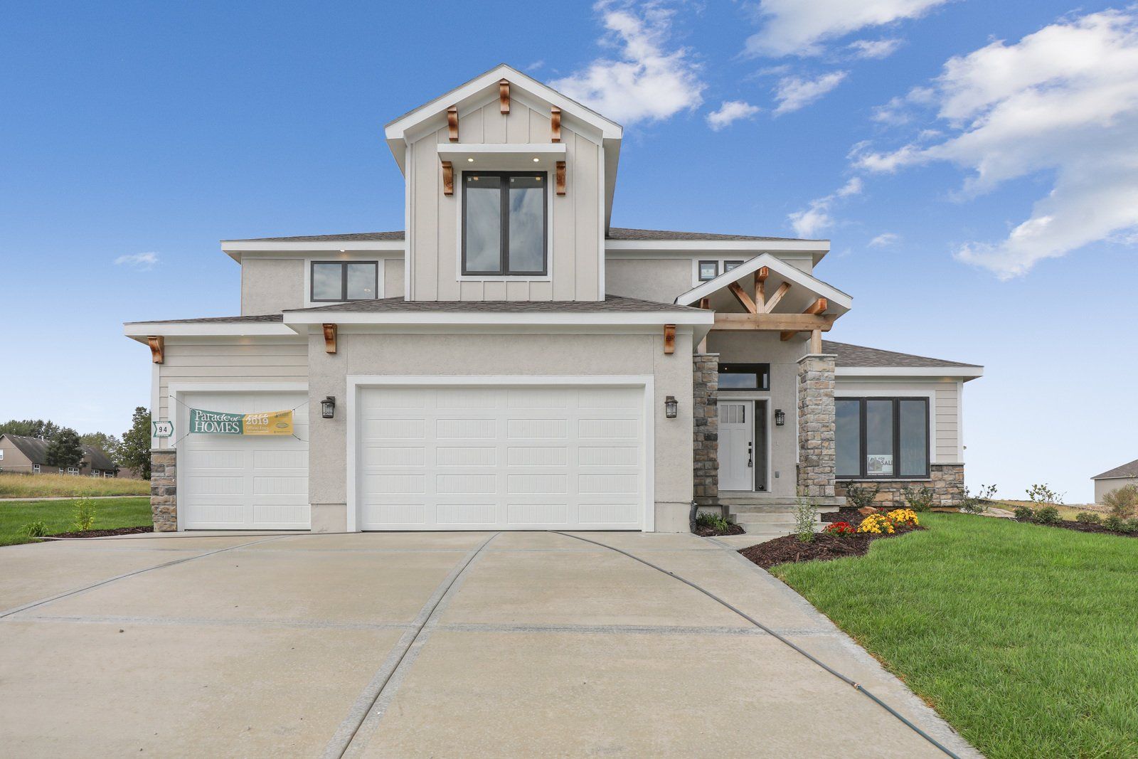 A large white house with two garage doors and a concrete driveway.