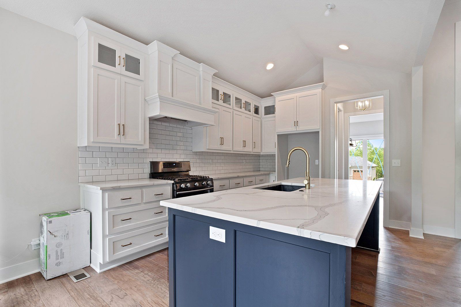 A kitchen with white cabinets and a blue island.