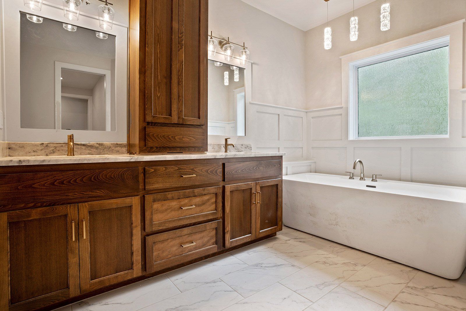 A bathroom with two sinks , a tub , a mirror and a window.