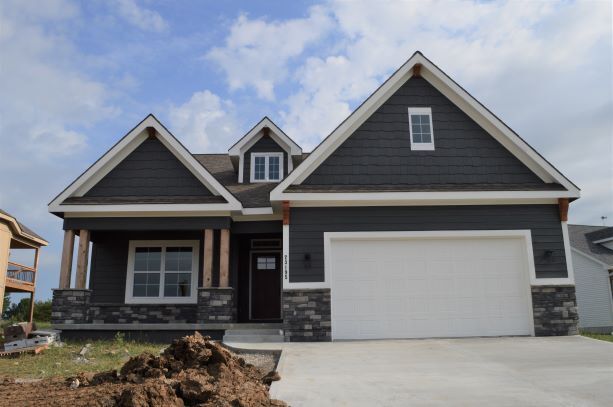 A large house with a white garage door and a large pile of dirt in front of it.