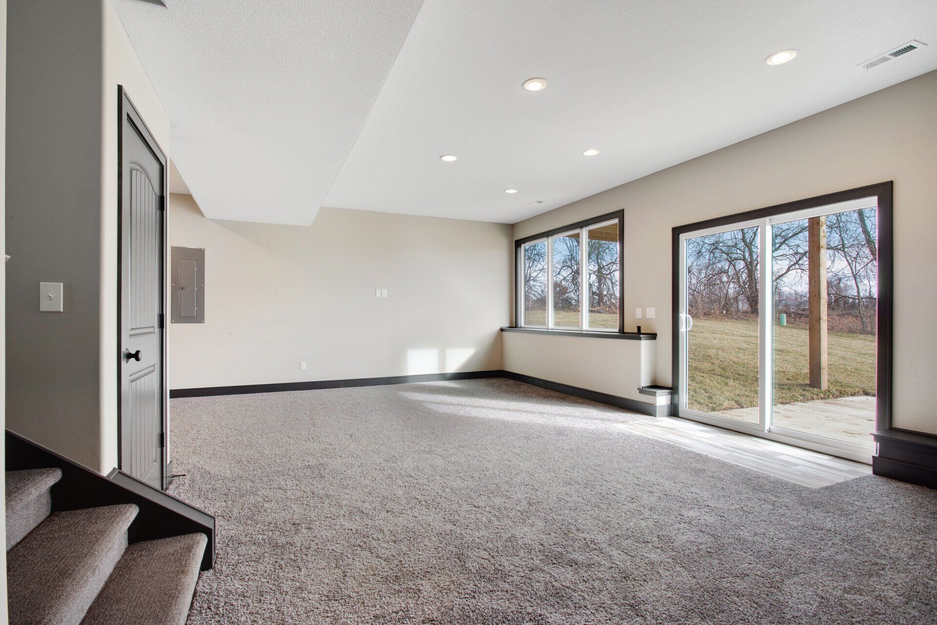 An empty basement with sliding glass doors and a lot of windows.
