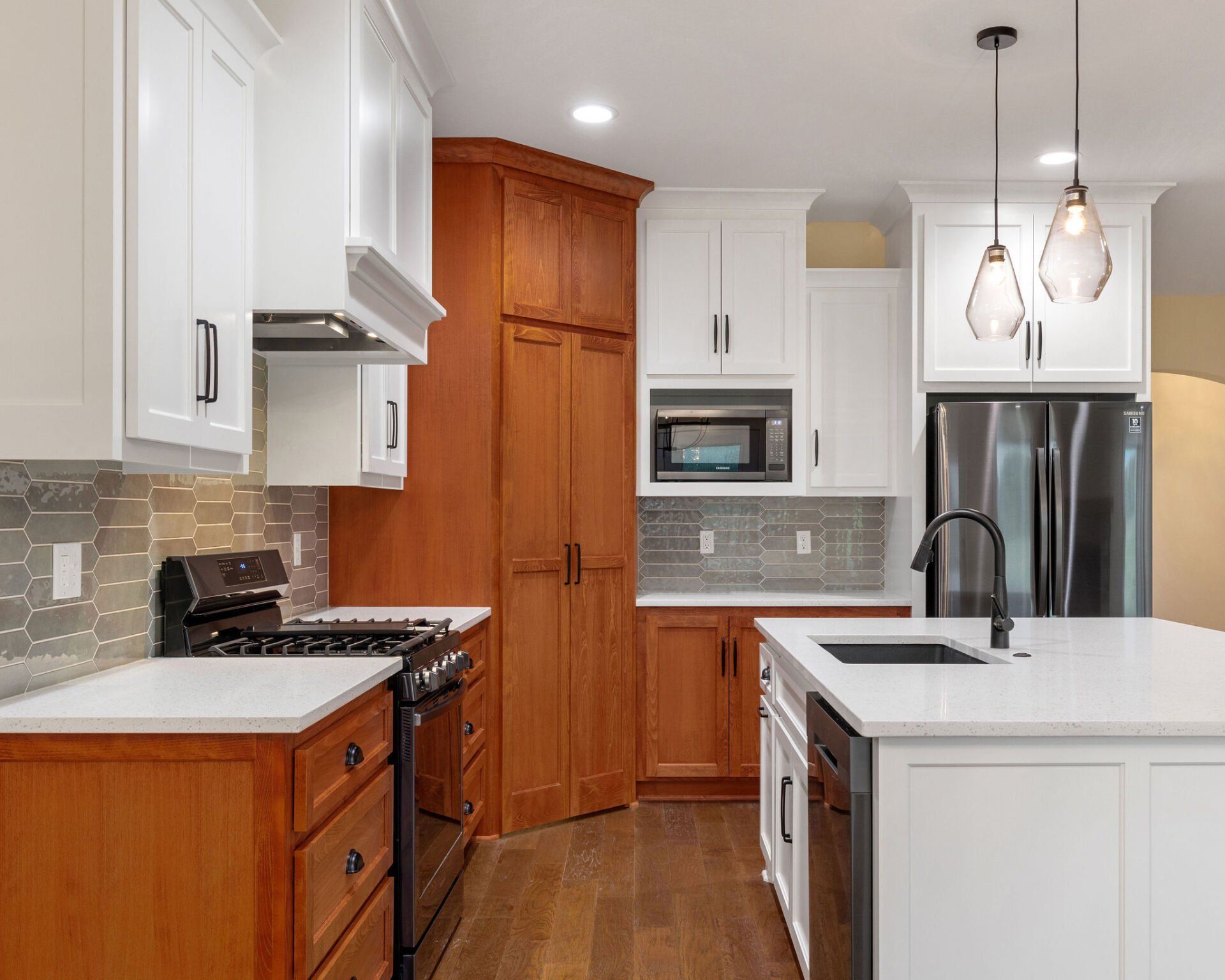 A kitchen with white cabinets , wooden cabinets , stainless steel appliances and a large island.