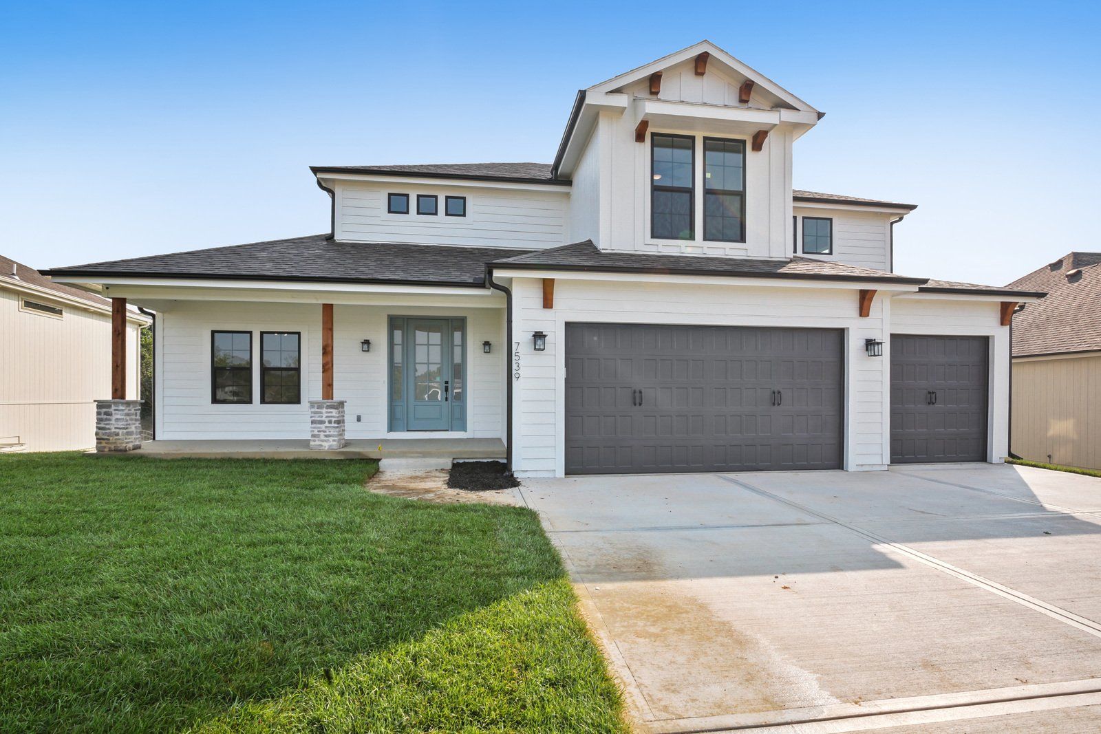 A large white house with three garage doors and a driveway.