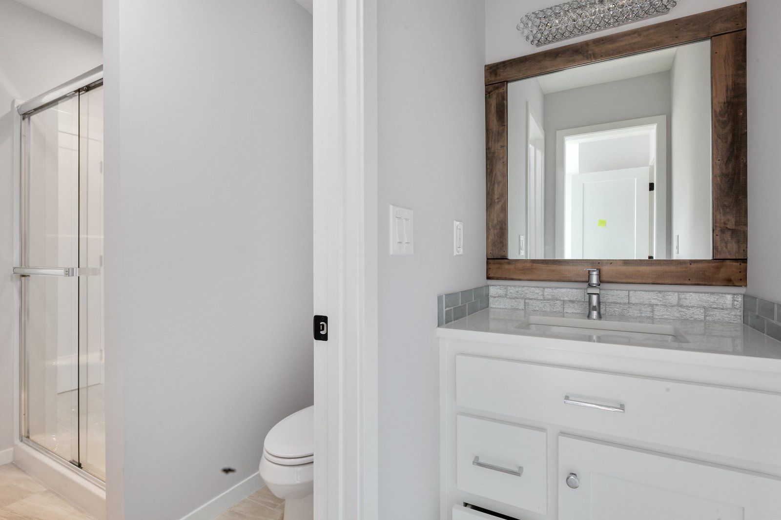 A bathroom with a toilet , sink , mirror and shower.