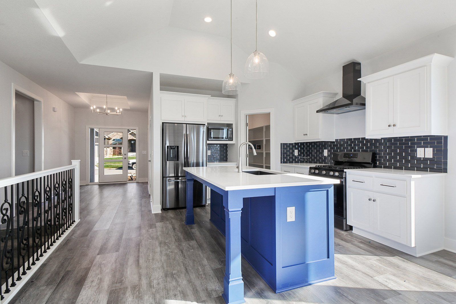 A kitchen with white cabinets and a blue island.