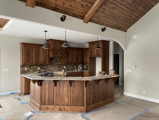 A kitchen with wooden cabinets and a large island in the middle.