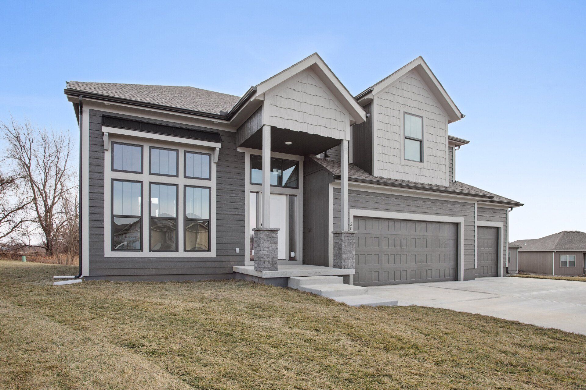 A large house with a lot of windows is sitting on top of a lush green field.