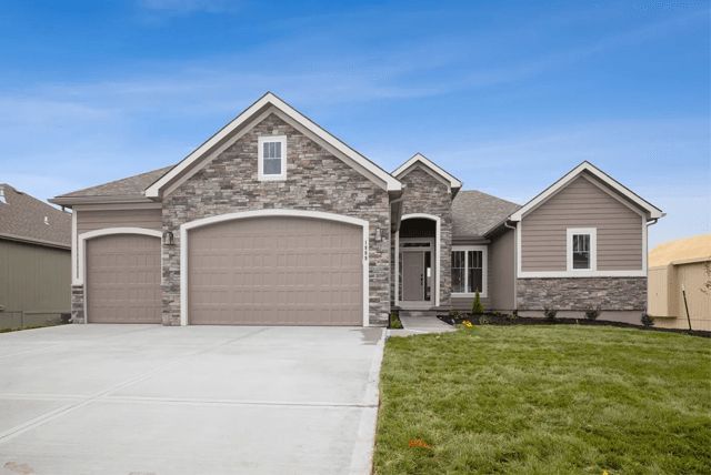A large house with two garage doors and a concrete driveway.