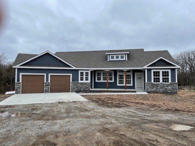 A blue house with two garage doors is sitting on top of a dirt field.