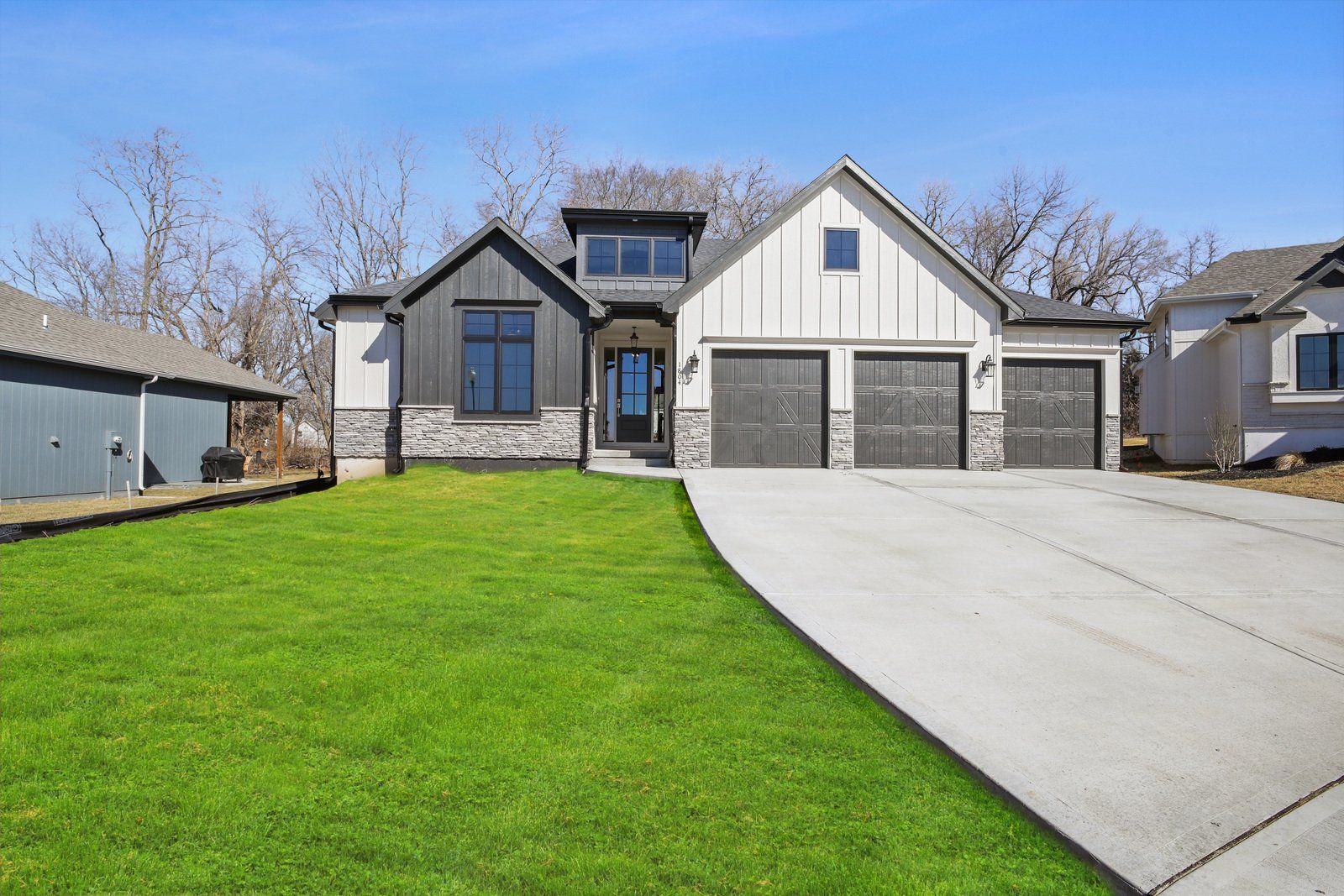 A large house with a lush green lawn and a driveway leading to it.