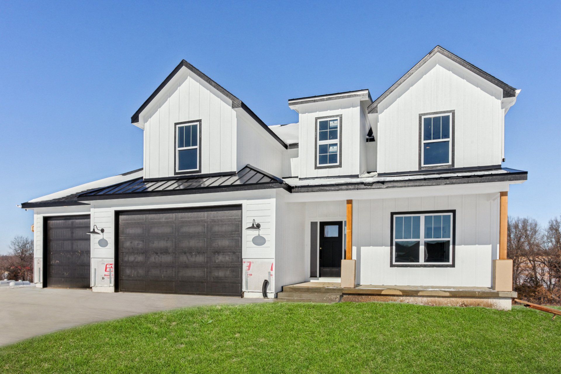 A large white house with two garages and a large lawn in front of it.