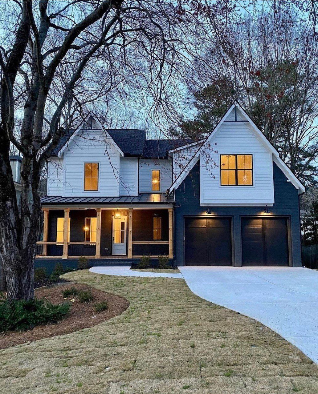 A black and white house with two garages and a driveway