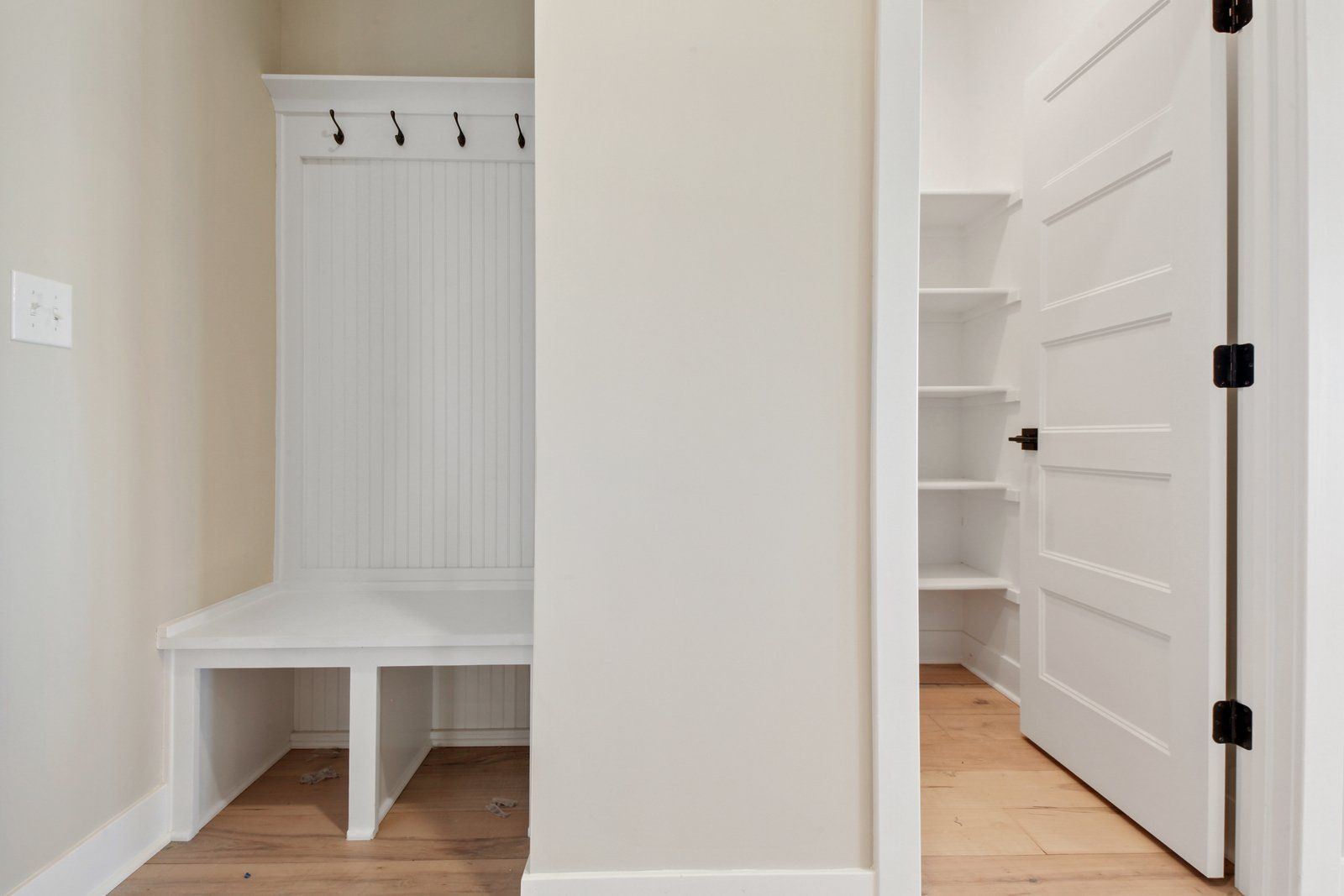 A hallway with a bench and a door leading to a closet.