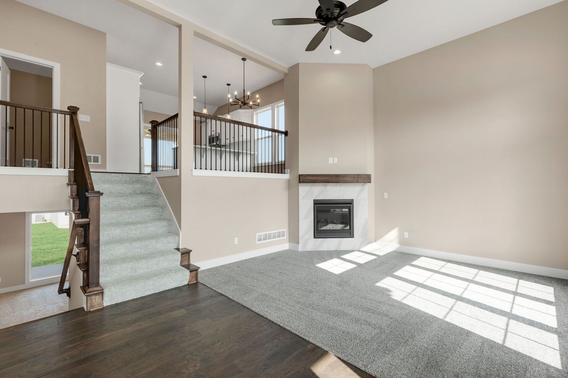 A living room with a fireplace , stairs and a ceiling fan.
