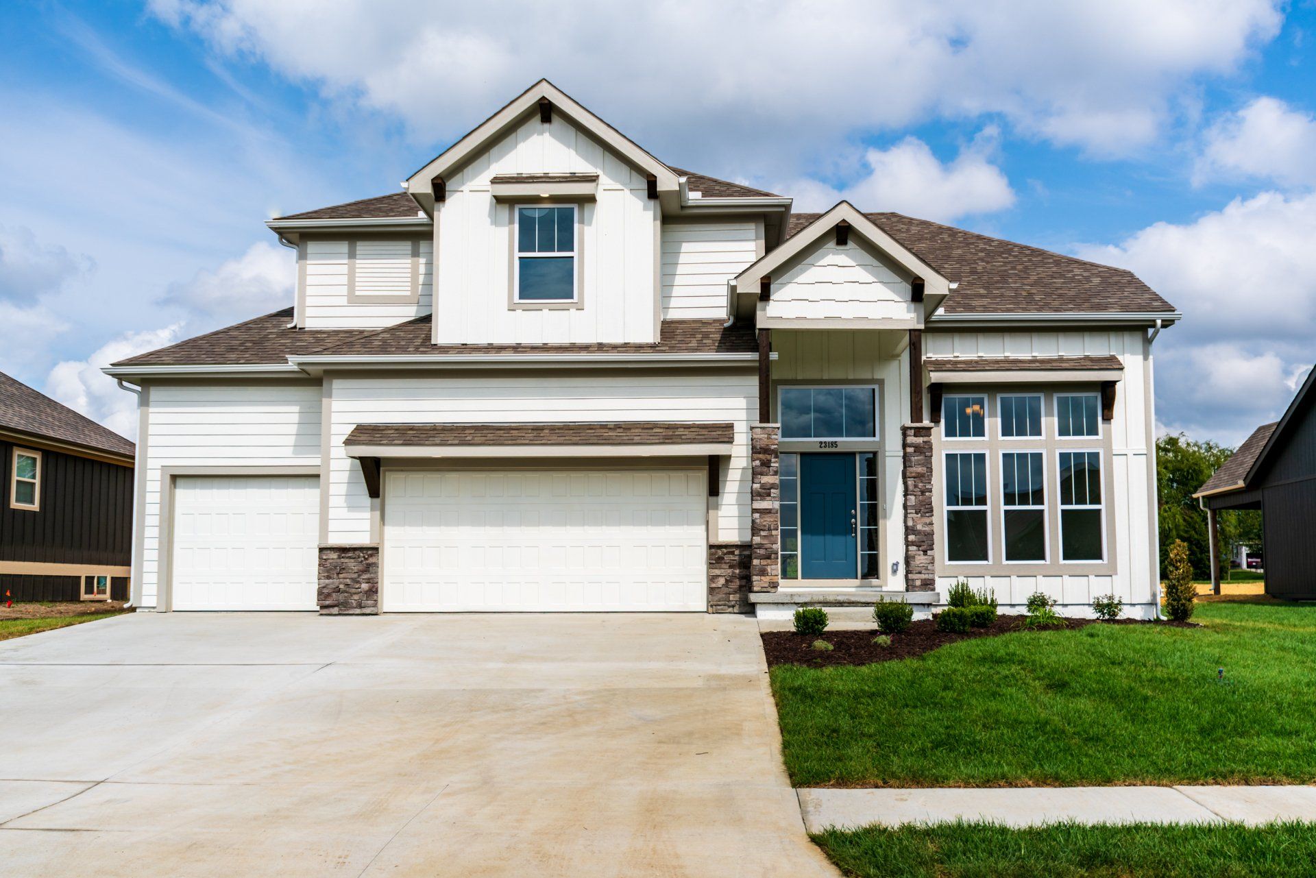 A large white house with a blue door and a large driveway.