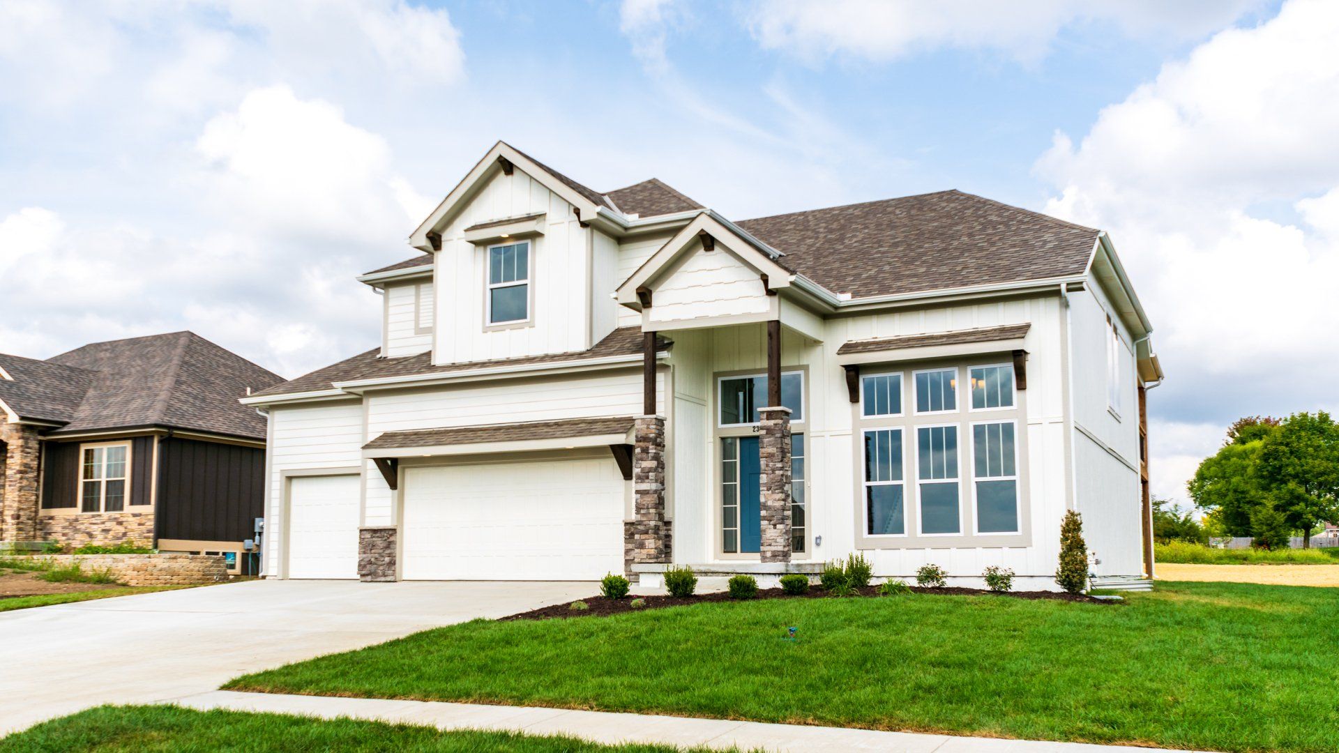 A large white house with a lush green lawn in front of it.