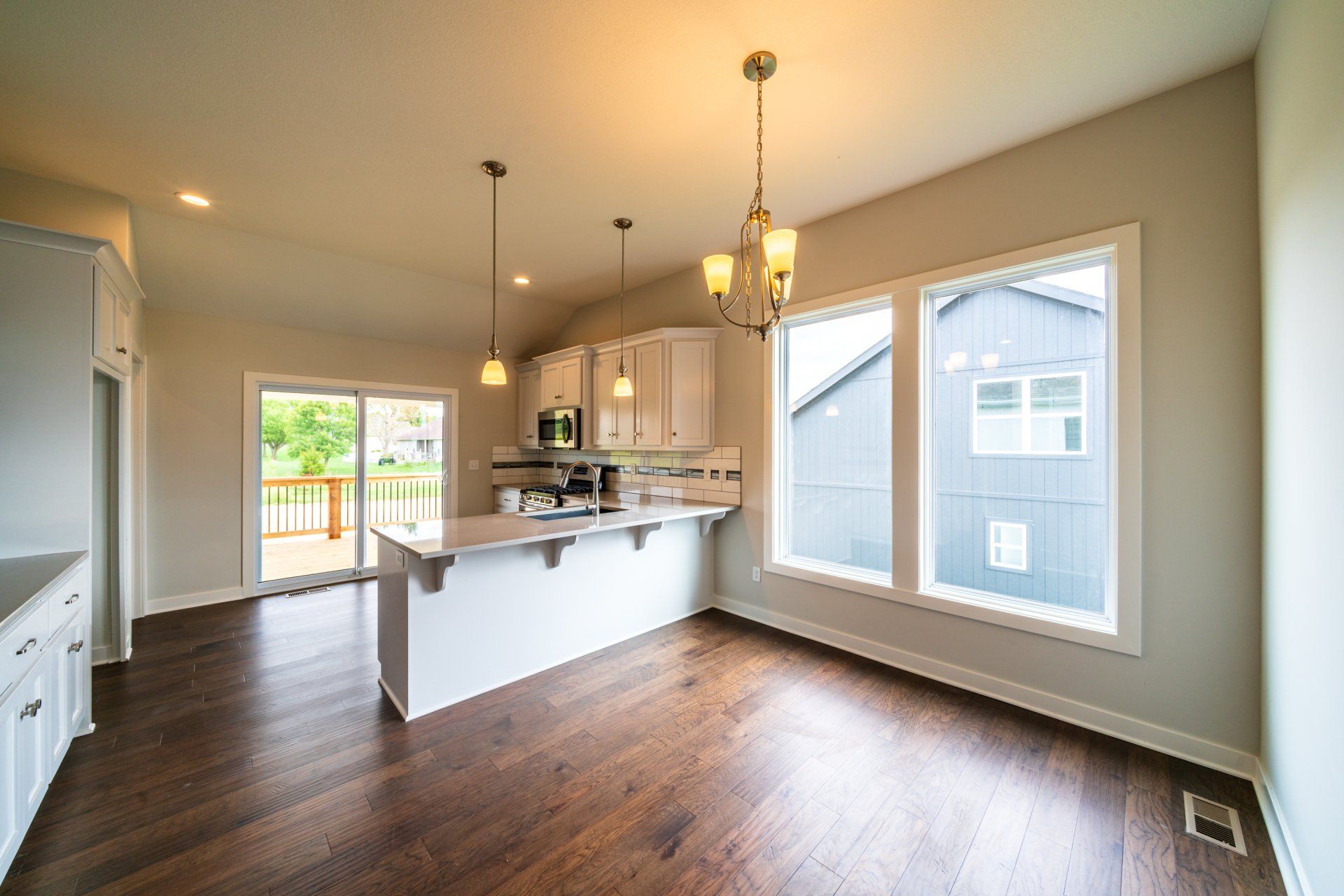 A kitchen and dining room in a house with hardwood floors and white cabinets.