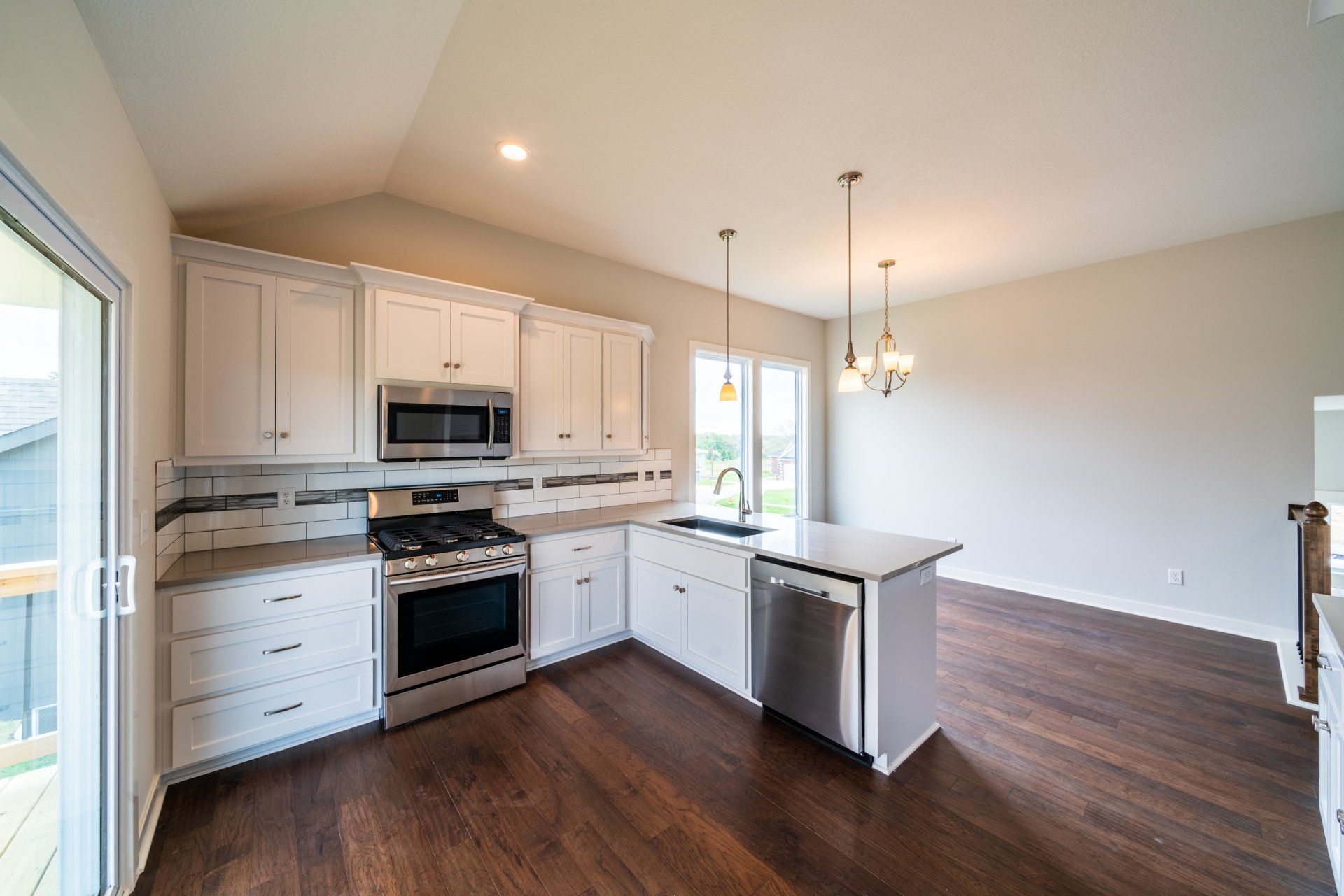 A kitchen with white cabinets , stainless steel appliances , and hardwood floors.