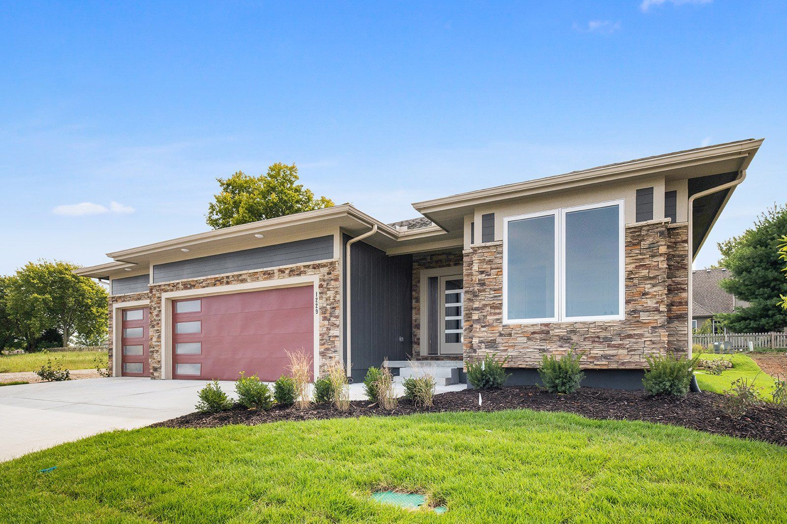 A house with a red garage door and a large window