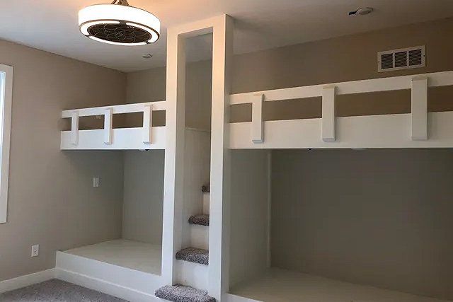 A bedroom with bunk beds and stairs in it