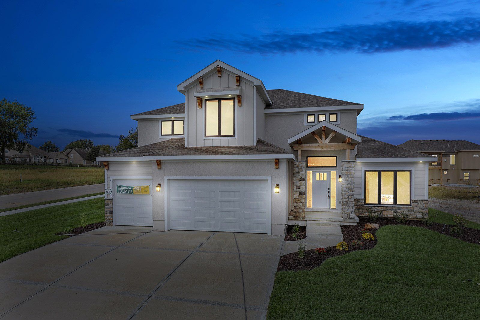A large white house with a large garage is lit up at night.