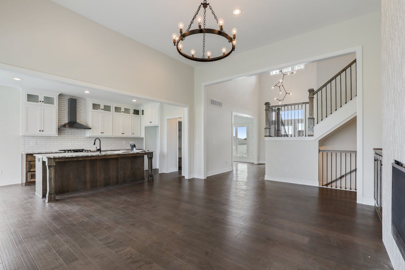 A large empty room with hardwood floors and a chandelier hanging from the ceiling.