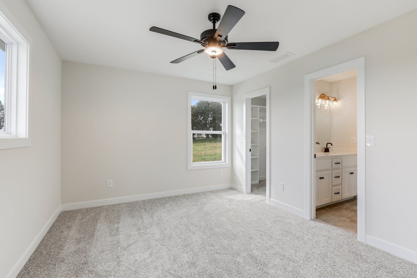 An empty bedroom with a ceiling fan and a window.