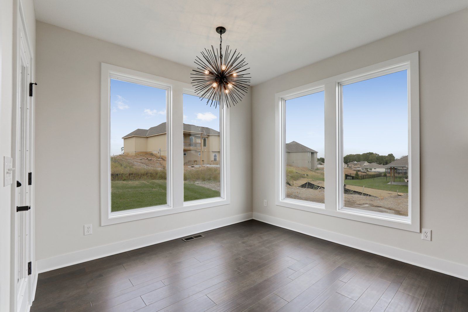An empty room with lots of windows and a chandelier.