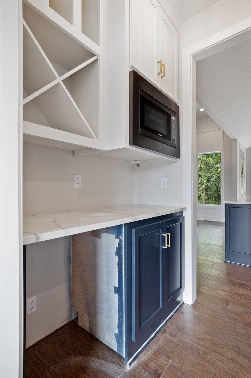A kitchen with a refrigerator , microwave , and wine rack.