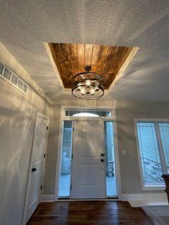 There is a chandelier hanging from the ceiling in the hallway.