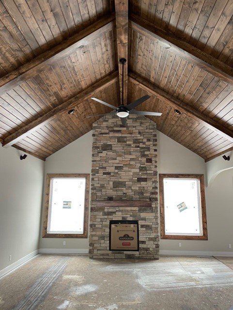 A living room with a vaulted ceiling and a stone fireplace