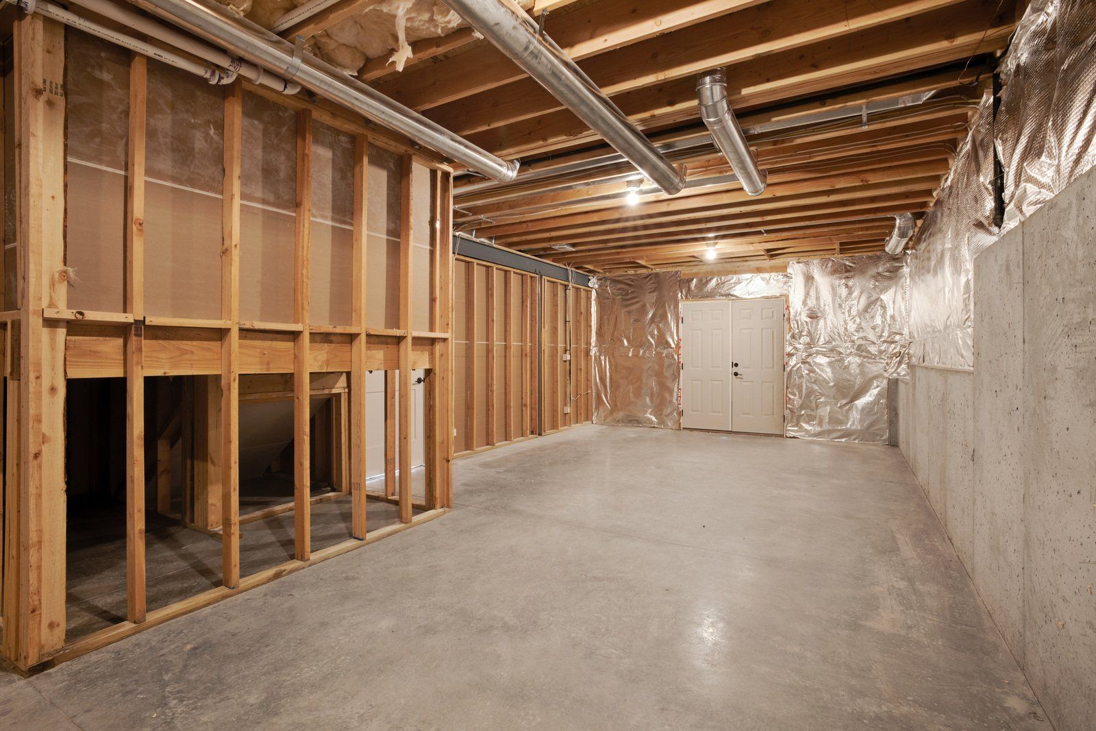 An empty basement with wooden walls and a concrete floor.