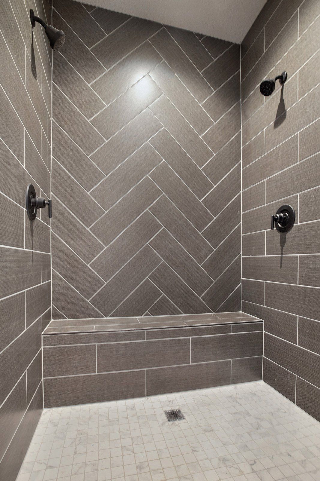 A shower with a bench and a herringbone pattern on the walls.