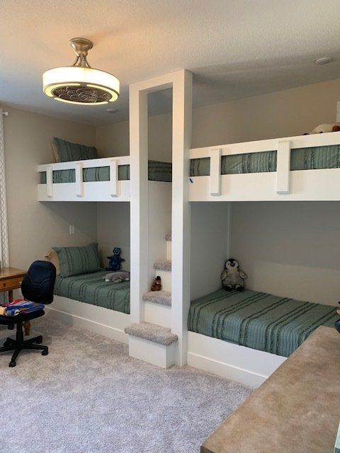 A bedroom with three bunk beds and a desk.