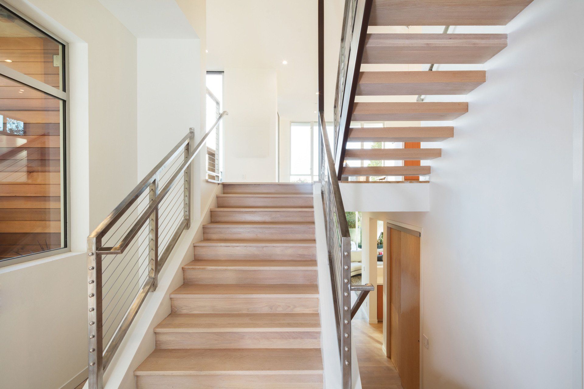 A staircase with a stainless steel railing and wooden steps