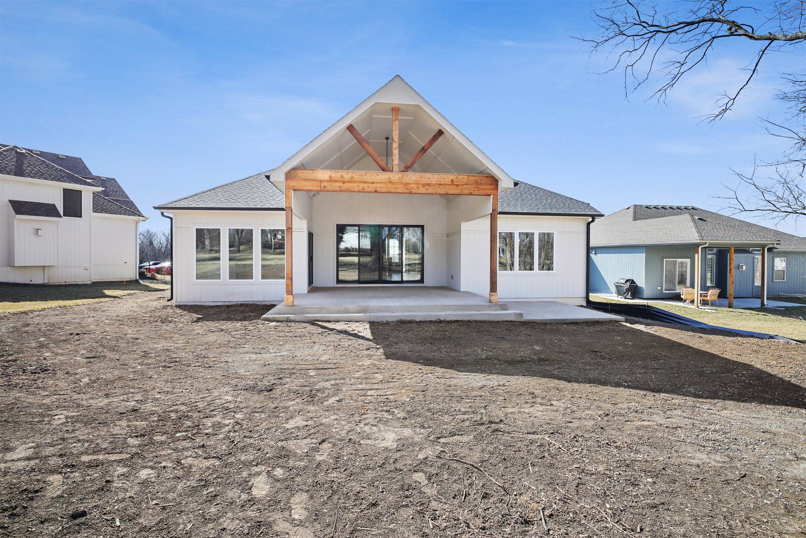 A large white house with a lot of windows is sitting on top of a dirt field.