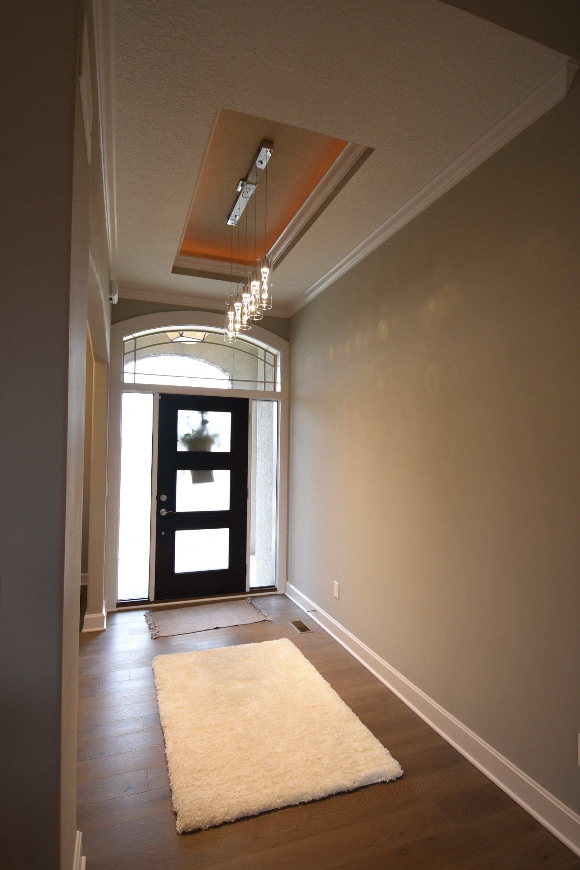 A hallway with a black door and a white rug