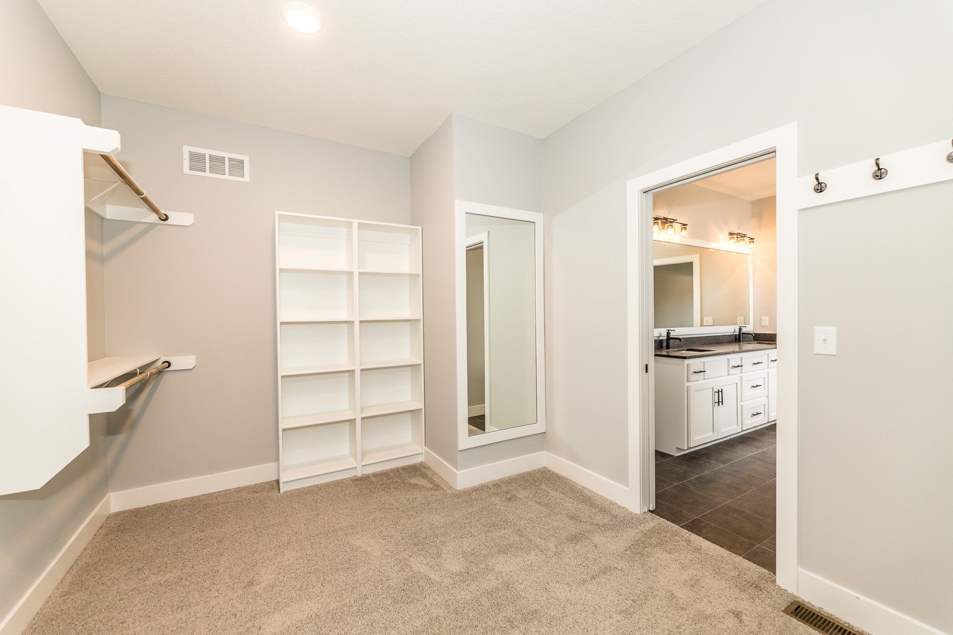 A walk in closet in a house with a large mirror and shelves.