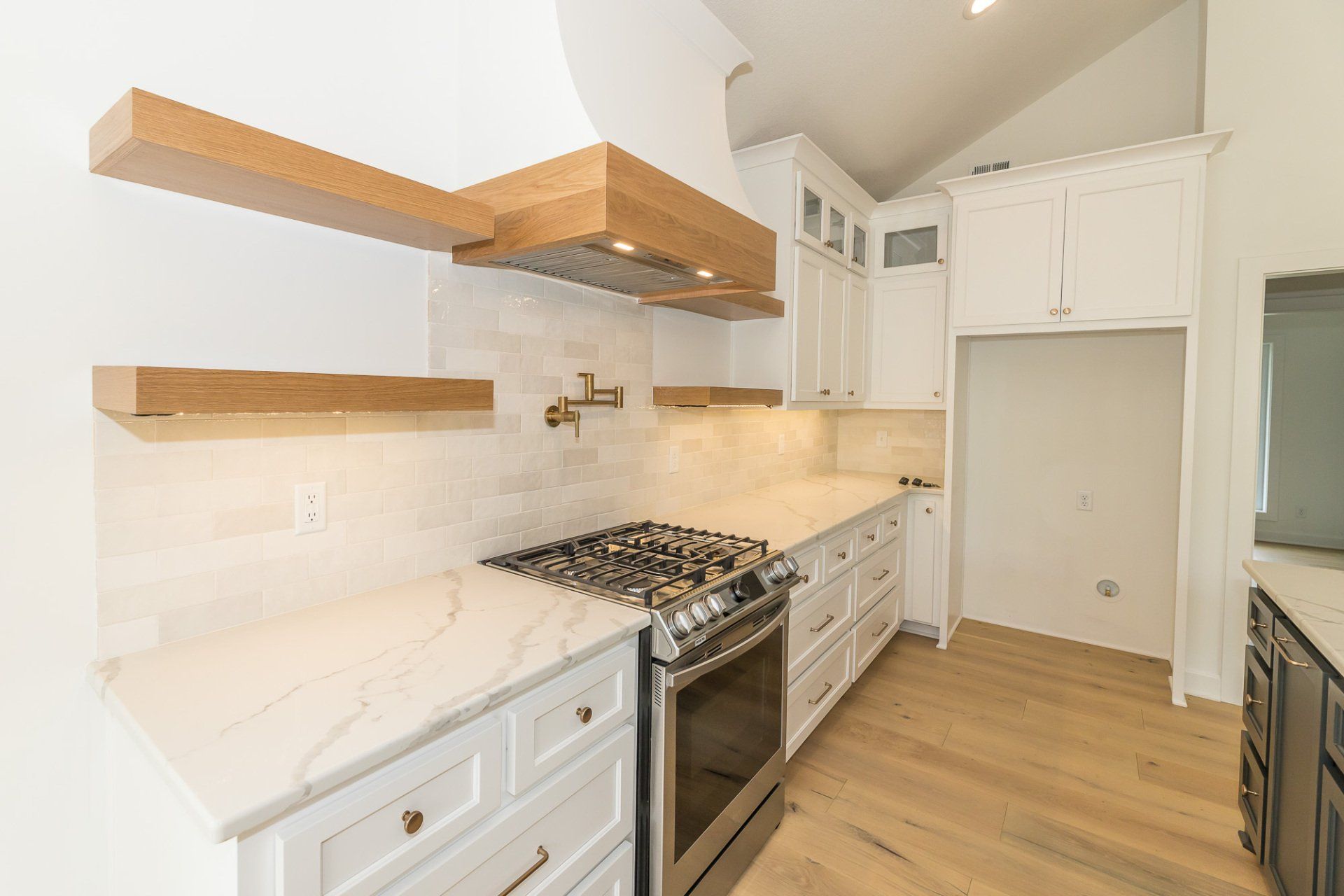A kitchen with white cabinets , a stove top oven , and a refrigerator.