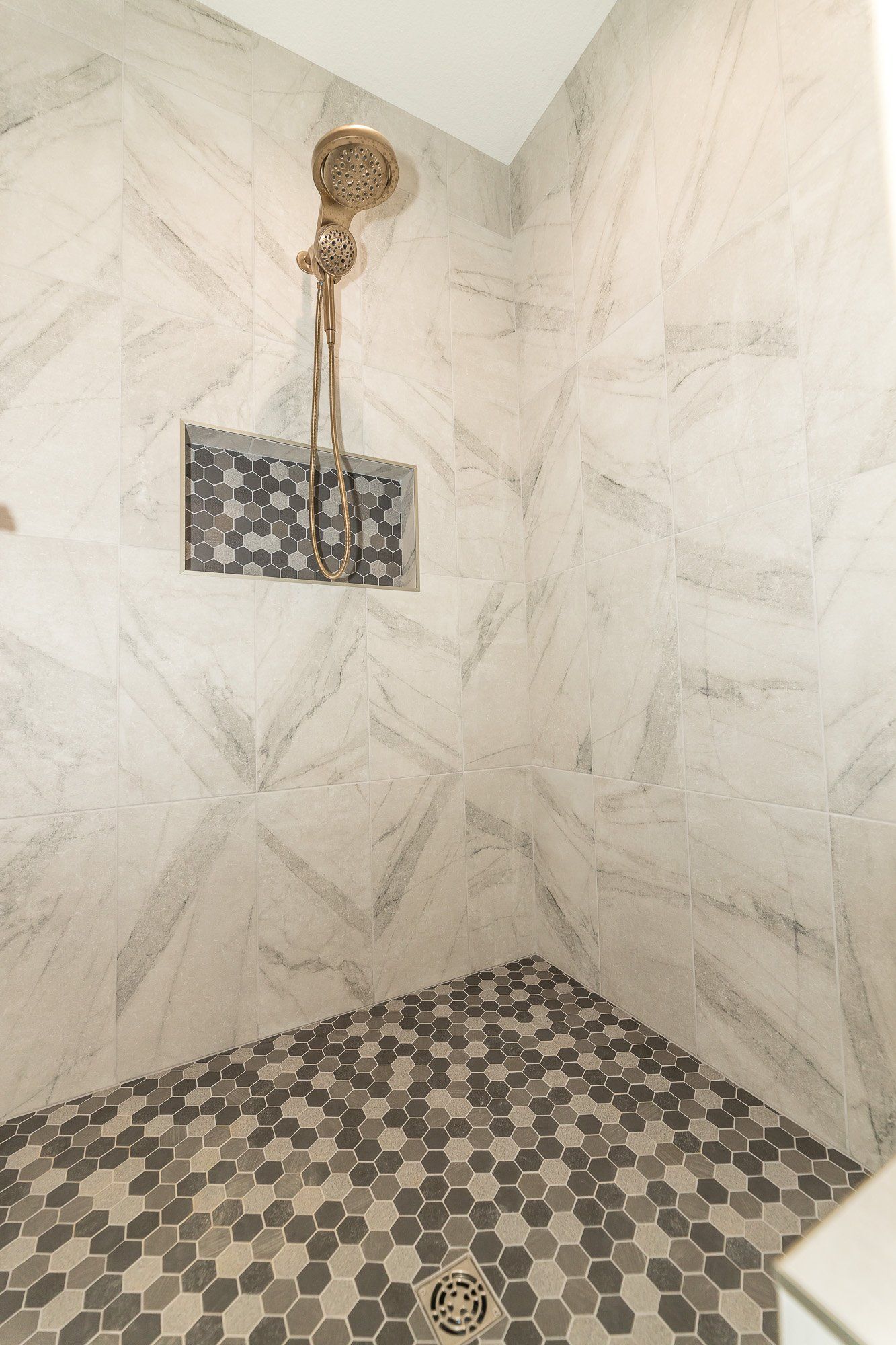 A shower with a shower head and a tiled floor.