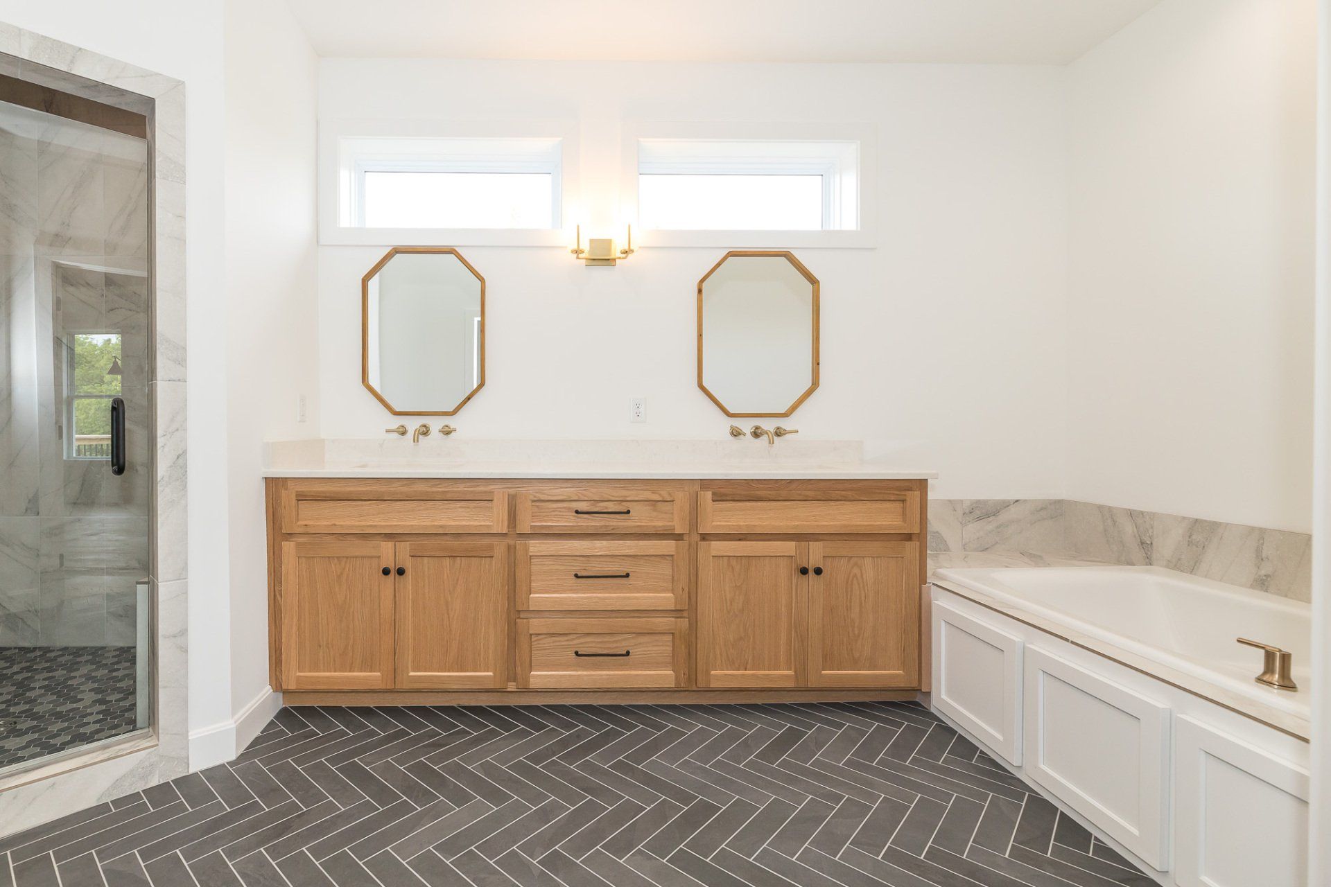 A bathroom with two sinks , a tub , and two mirrors.