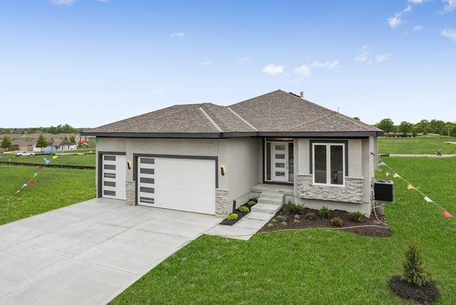 An aerial view of a house with a large driveway in a residential area.