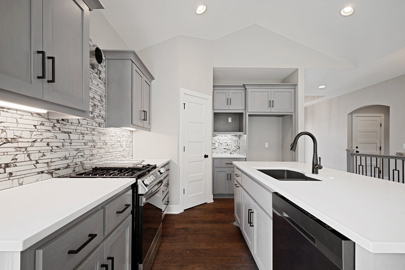 A kitchen with gray cabinets and white counter tops