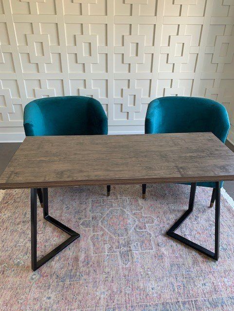 A wooden table with two blue chairs on a rug.