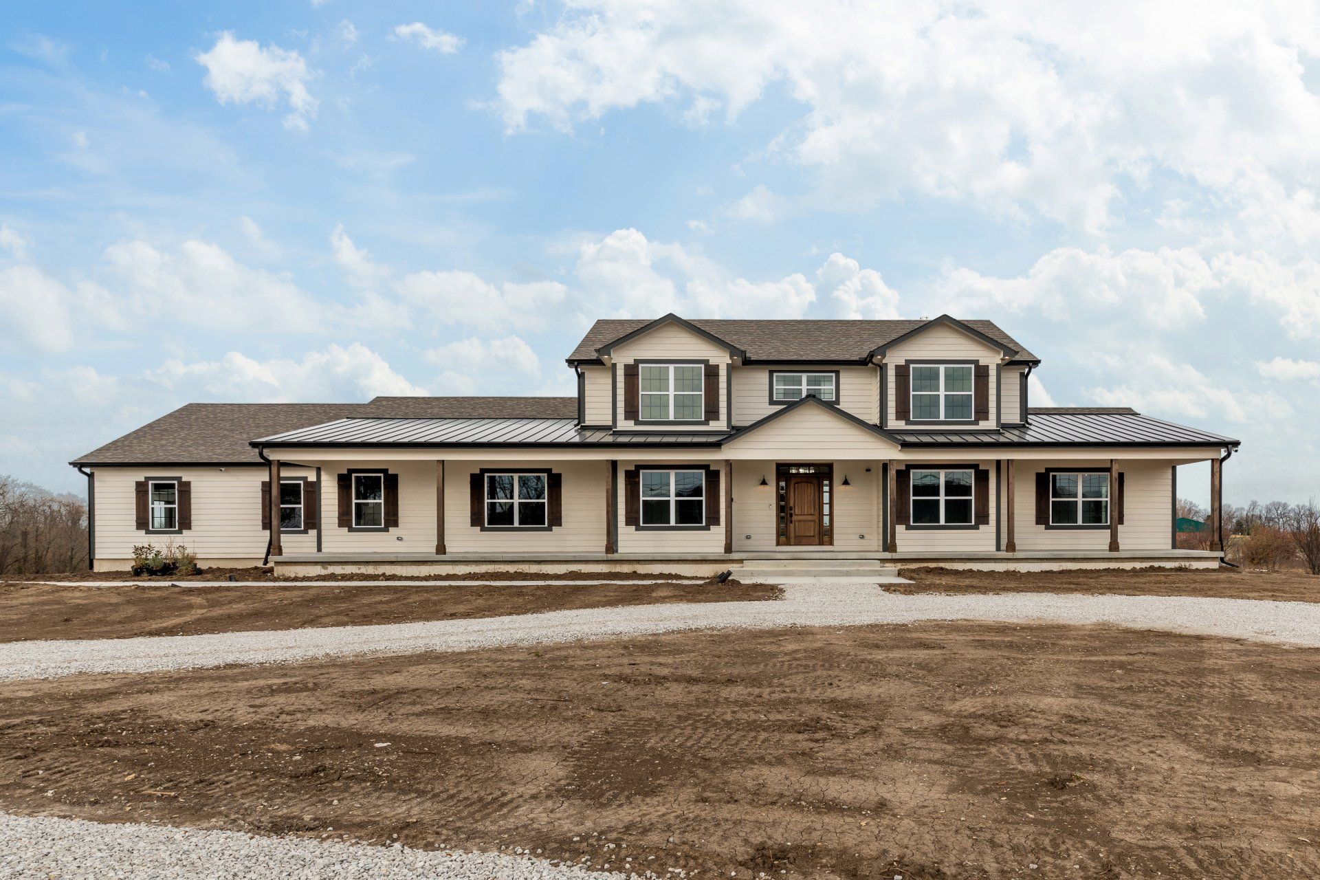 A large house with a lot of windows is sitting on top of a dirt field.