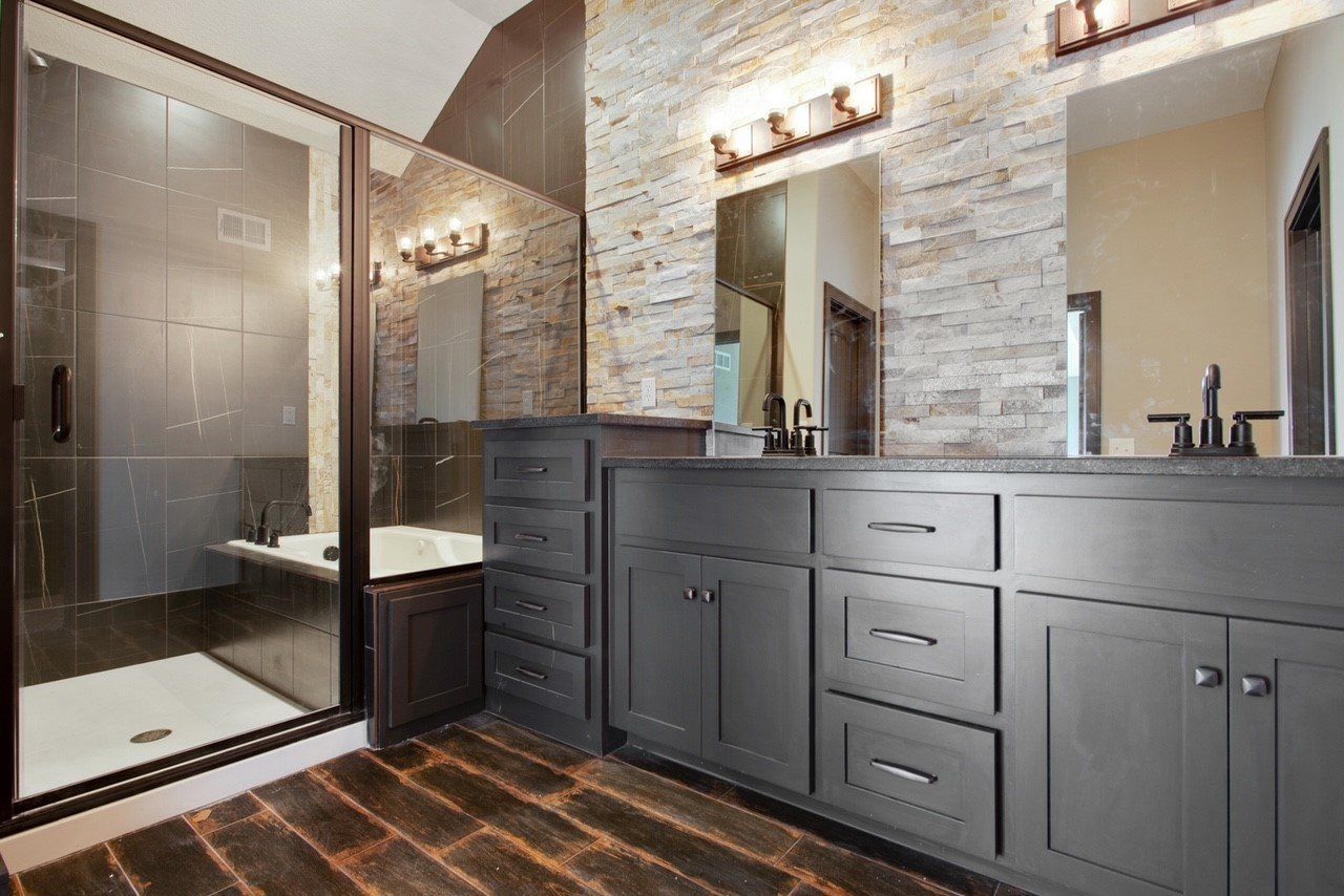 A bathroom with two sinks , a tub , and a walk in shower.